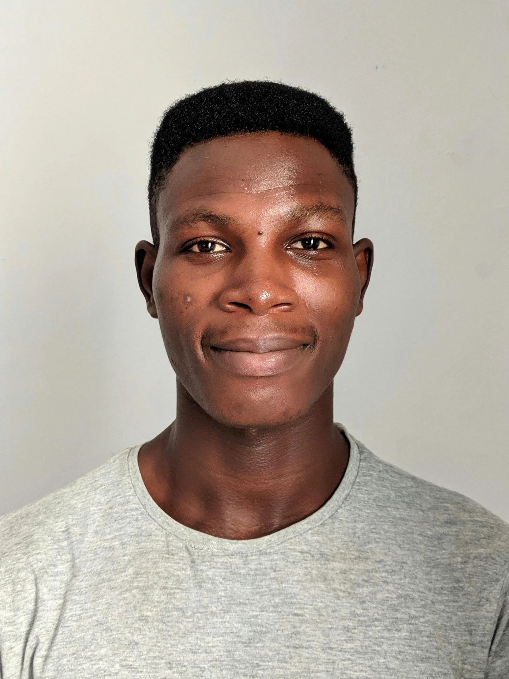 a man standing in front of a white wall, by Chinwe Chukwuogo-Roy, halfbody headshot, he is about 20 years old | short, indoor picture, taken in 2 0 2 0