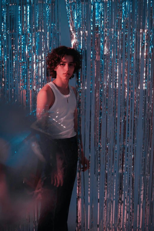a woman standing in front of a curtain, inspired by Nan Goldin, trending on pexels, magical realism, young middle eastern woman, disco party, beautiful boy, blueish