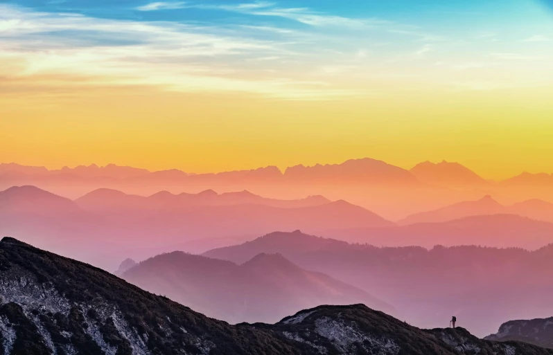 a person standing on top of a mountain at sunset, pexels contest winner, romanticism, multicoloured, alps, layers of strata, sunset panorama