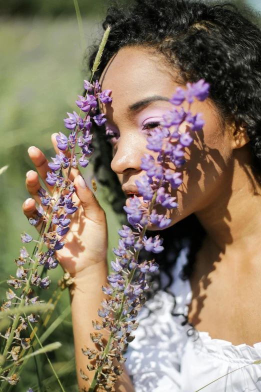 a woman holding purple flowers in front of her face, trending on pexels, renaissance, black young woman, made of wildflowers, salvia, photoshoot for skincare brand