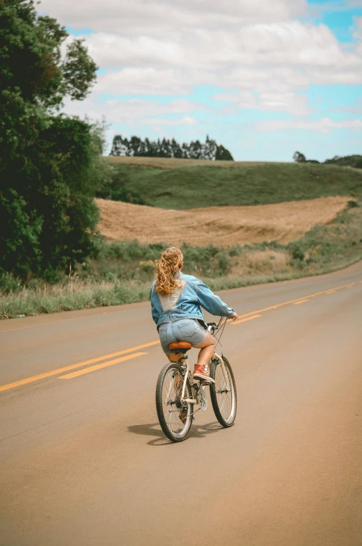 a woman riding a bike down the middle of a road, in the countryside, #trending, sports photo, decorative