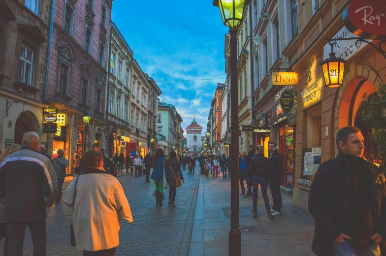 a group of people walking down a street next to tall buildings, by Emma Andijewska, pexels contest winner, viennese actionism, gas lamps, in a medieval city, lots of shops, rutkowskyi