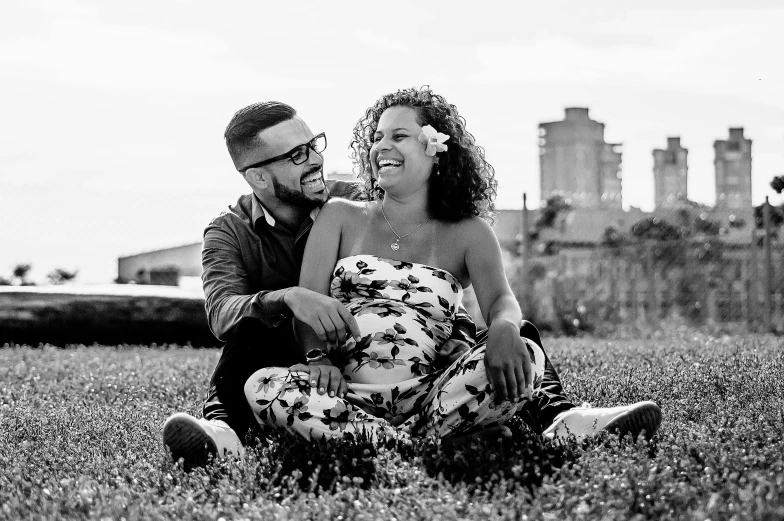 a man and a woman are sitting in the grass, a black and white photo, by Dan Frazier, pexels, beautiful city black woman only, maternal, on rooftop, happy couple
