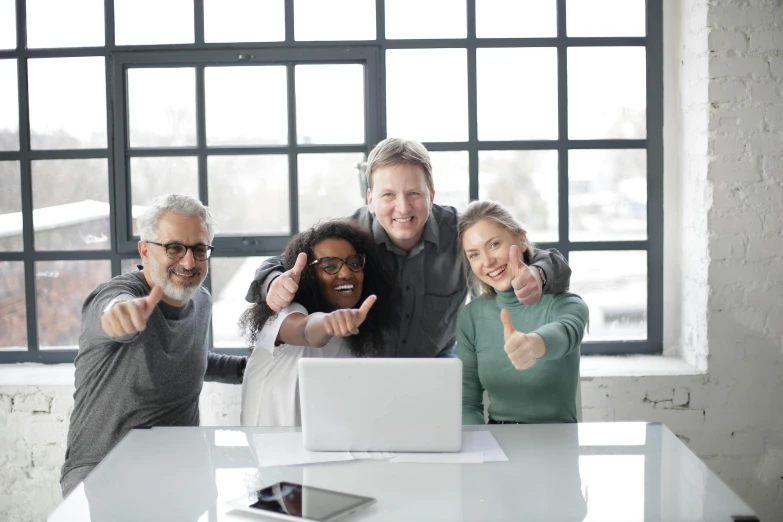 a group of people sitting around a table with a laptop, pointing at the camera, avatar image, high-quality photo, maintenance photo