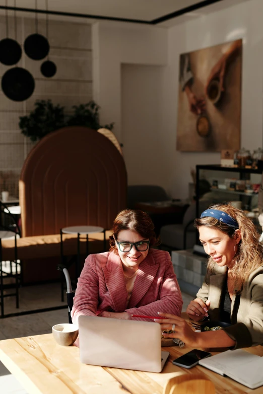 a couple of women sitting at a table with a laptop, a portrait, by Anita Malfatti, trending on unsplash, high quality picture, cafe, very stylish, 15081959 21121991 01012000 4k