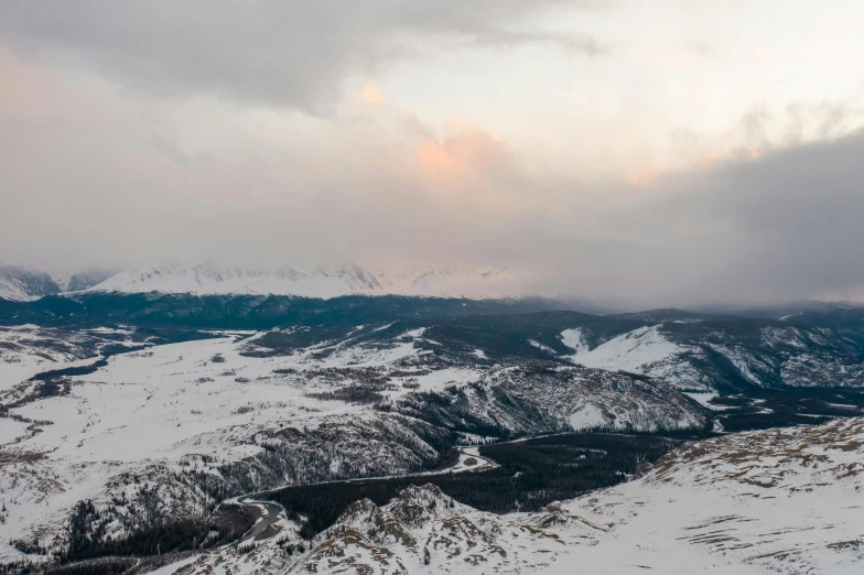 a person standing on top of a snow covered mountain, by Emma Andijewska, pexels contest winner, hurufiyya, colorado mountains, stormy setting, view from above, panoramic