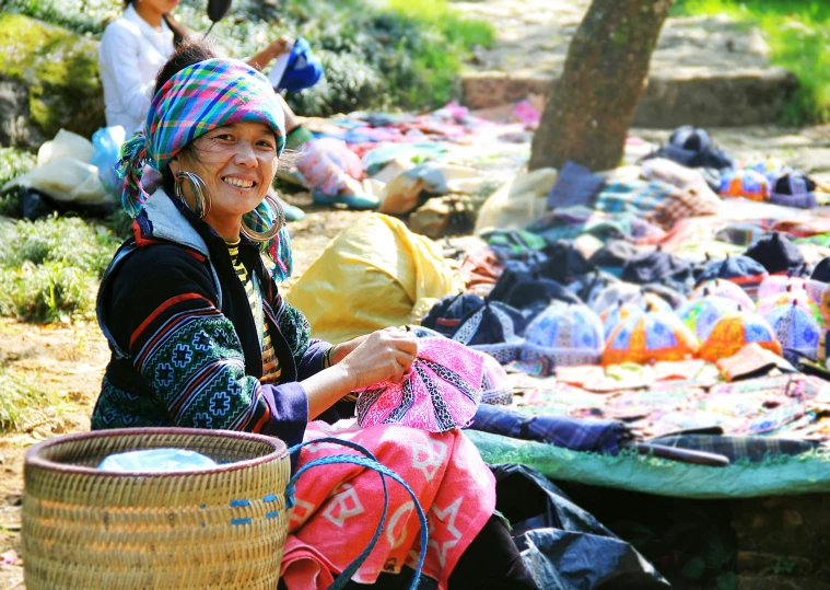 a woman sitting next to a pile of clothes, crafts and souvenirs, ja mong, thumbnail, highlight