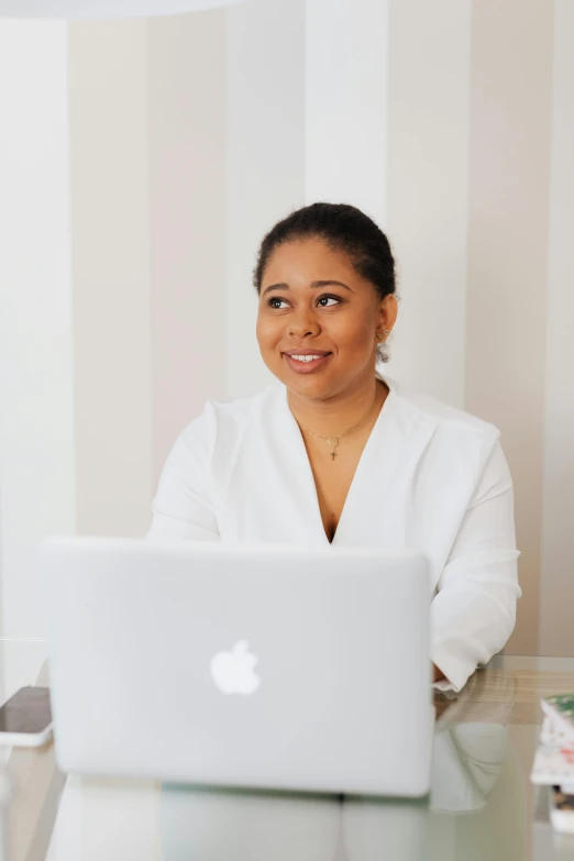 a woman sitting in front of a laptop computer, by Dulah Marie Evans, dressed in white, clean glow, vp of marketing, riyahd cassiem