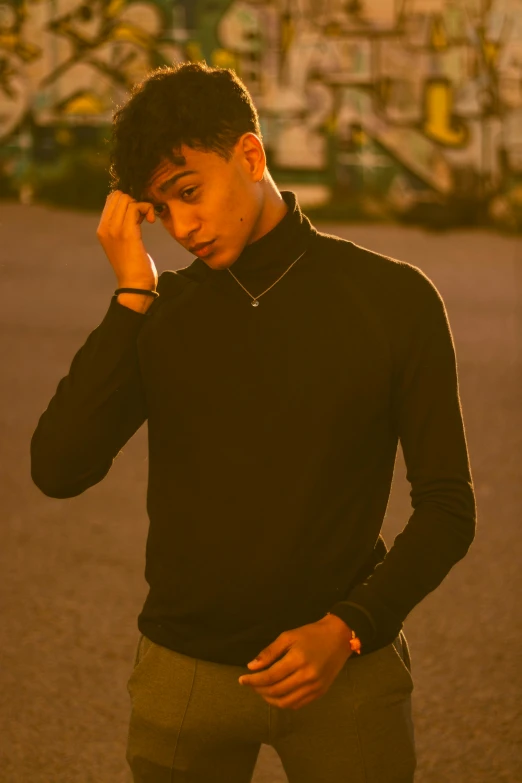 a young man standing in front of a graffiti covered wall, an album cover, by Cosmo Alexander, trending on pexels, renaissance, black turtle neck shirt, at dusk at golden hour, jewelry, shigeto koyama