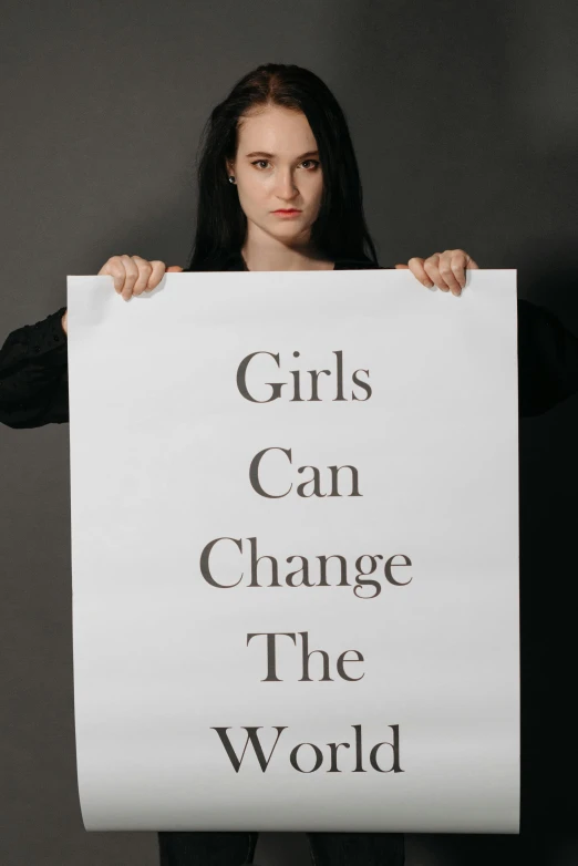 a woman holding a sign that says girls can change the world, a poster, by Anna Katharina Block, pexels contest winner, advertisement poster, half body photo, teenager, fashion poster