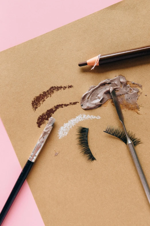 a couple of pencils sitting on top of a piece of paper, a photorealistic painting, inspired by Mac Conner, trending on pexels, lots of makeup, taupe, lashes, knolling