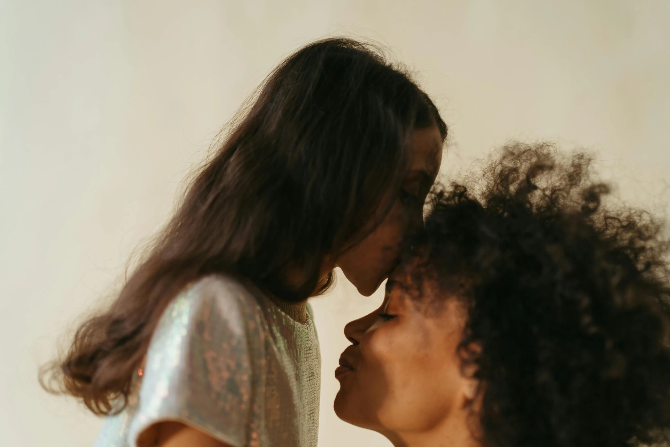 a woman and a little girl standing next to each other, pexels contest winner, romanticism, lesbian kiss, long afro hair, slightly pixelated, bedhead