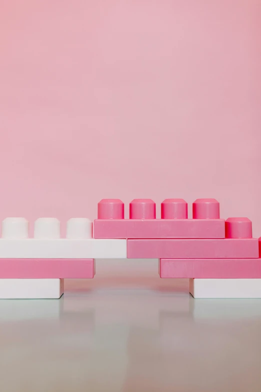 a couple of pink legos sitting on top of a table, an abstract sculpture, inspired by Rachel Whiteread, unsplash, lined up horizontally, promo image, milk, bumps