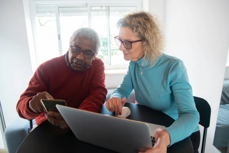 a man and woman sitting at a table looking at a laptop, two aboriginal elders, low quality photo, realistic », healthcare