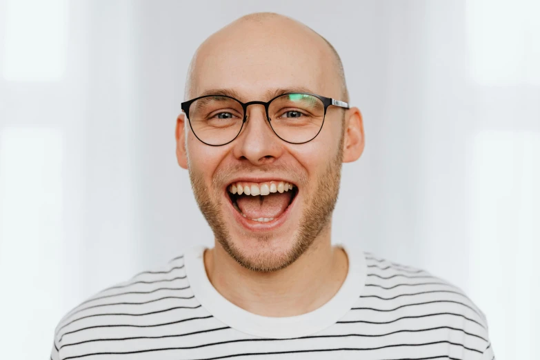 a bald man wearing glasses and a striped shirt, inspired by Leo Leuppi, pexels contest winner, smileing nright, daniil kudriavtsev, all teeth, heath clifford