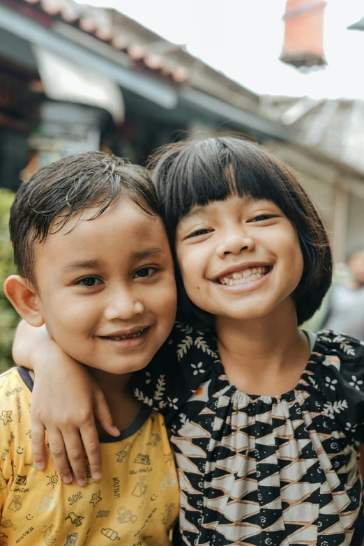 a couple of kids standing next to each other, pexels contest winner, sumatraism, slight friendly smile, square, embracing, headshot