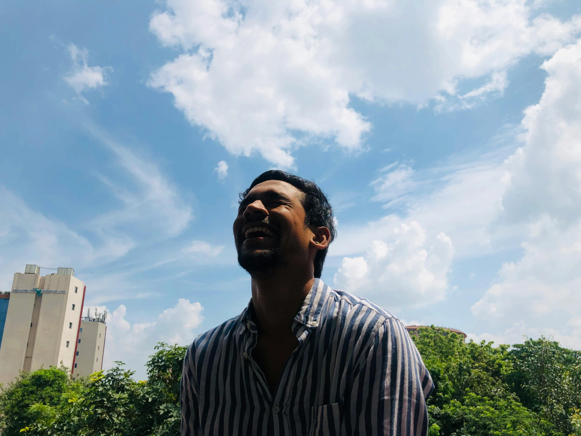 a man in a striped shirt is flying a kite, an album cover, inspired by Sunil Das, pexels contest winner, happy clouds behind, portrait of tall, profile image, standing on rooftop