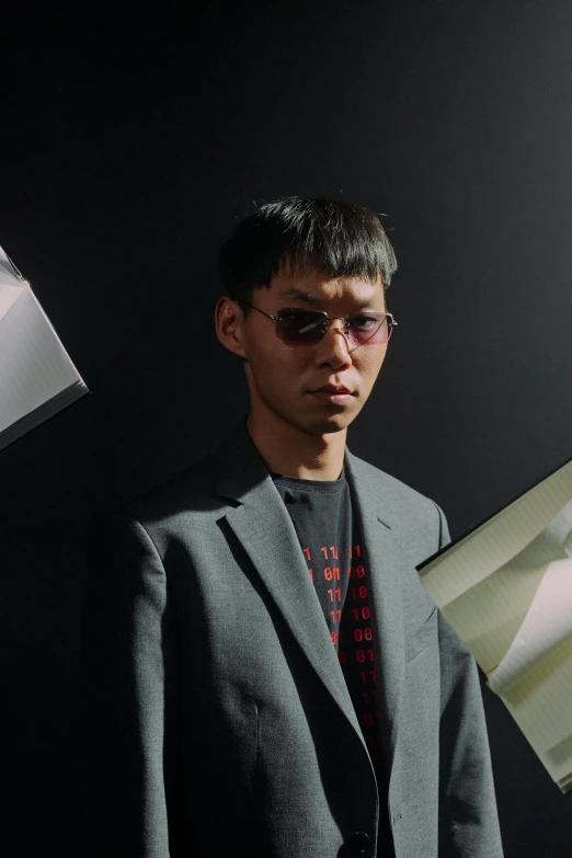 a man in a suit holding a piece of paper, an album cover, inspired by Yanjun Cheng, unsplash, neo-dada, futuristic sunglasses, half asian, wearing space techwear, highly reflective light