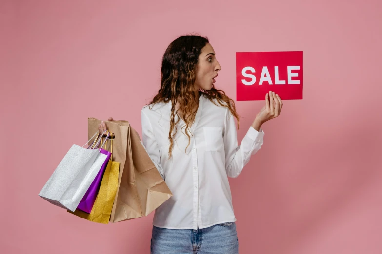a woman holding shopping bags and a sale sign, pexels contest winner, avatar image, loose - fitting blouses, pink clothes, professional image