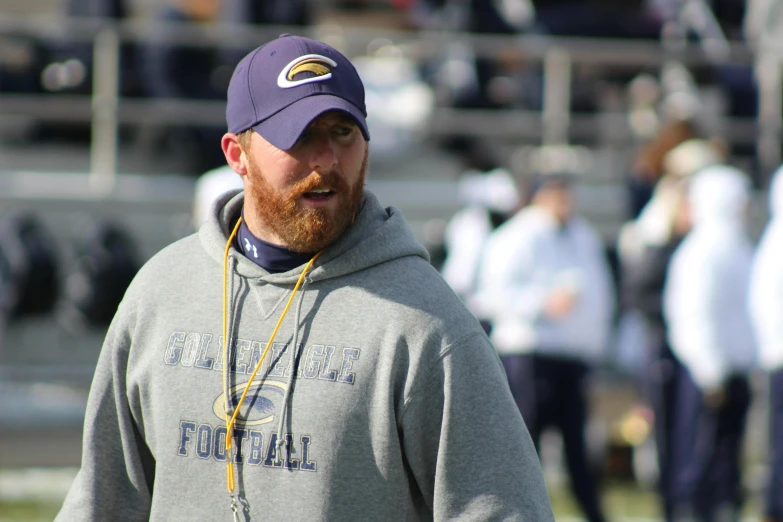 a man with a beard standing on a field, dylan cole, sports photo, glenn brown, pitt