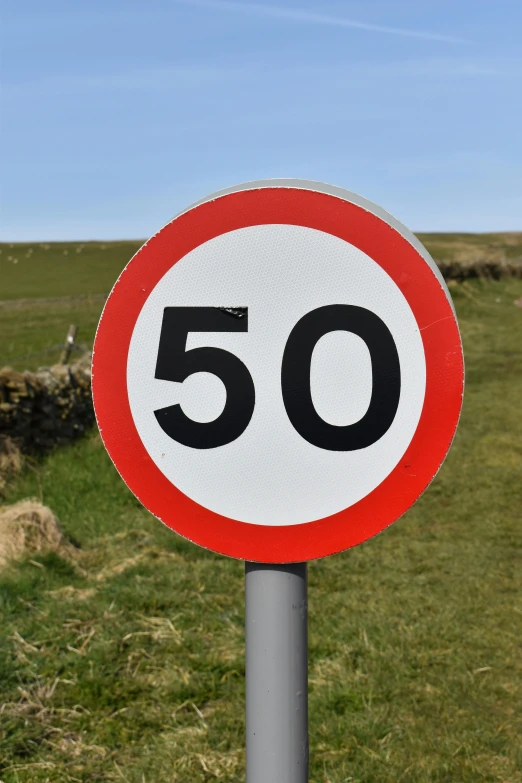 a speed limit sign sitting on the side of a road, by David Simpson, orkney islands, -step 50, hillside, on a village