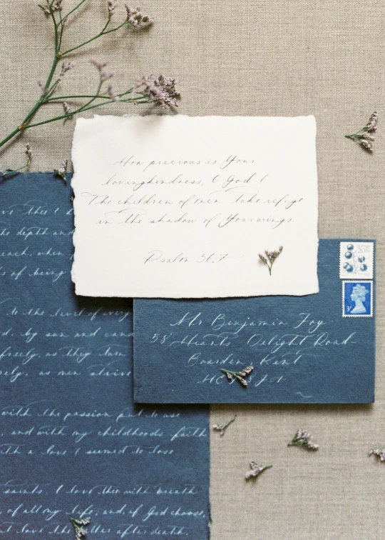 a piece of paper sitting on top of a table, inspired by Louisa Chase, private press, navy-blue, in romantic style, slate, calligraphy