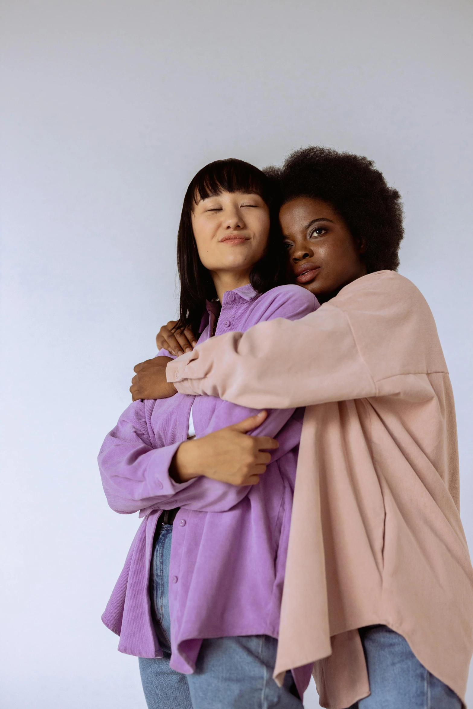 a couple of women standing next to each other, trending on pexels, purple skin color, hugs, pastel clothing, wearing a robe