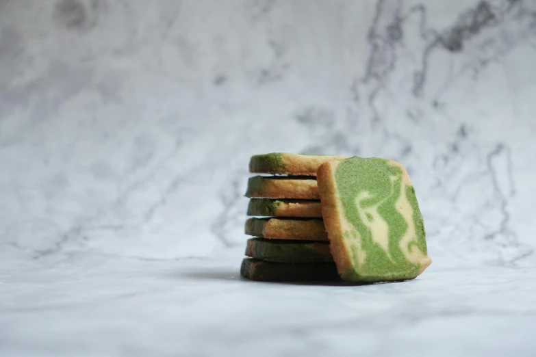 a stack of cookies sitting on top of a counter, inspired by Richmond Barthé, unsplash, art nouveau, leaf green, dazzle camouflage, japanese collection product, view from the side