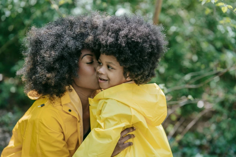 a woman in a yellow raincoat hugging a little girl in a yellow raincoat, by Nina Hamnett, pexels, black man with afro hair, with textured hair and skin, thumbnail, kissing smile