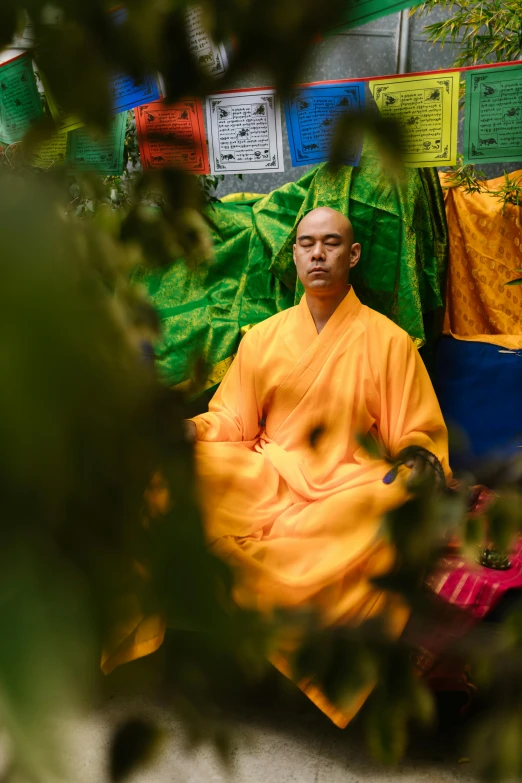 a man in a yellow robe sitting on the ground, inspired by Li Di, unsplash, lush surroundings, centered face shot, beijing, full colour