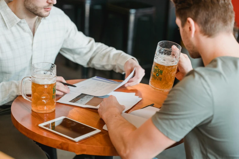 a couple of men that are sitting at a table, pexels contest winner, beer glasses, character sheets on table, customers, thumbnail