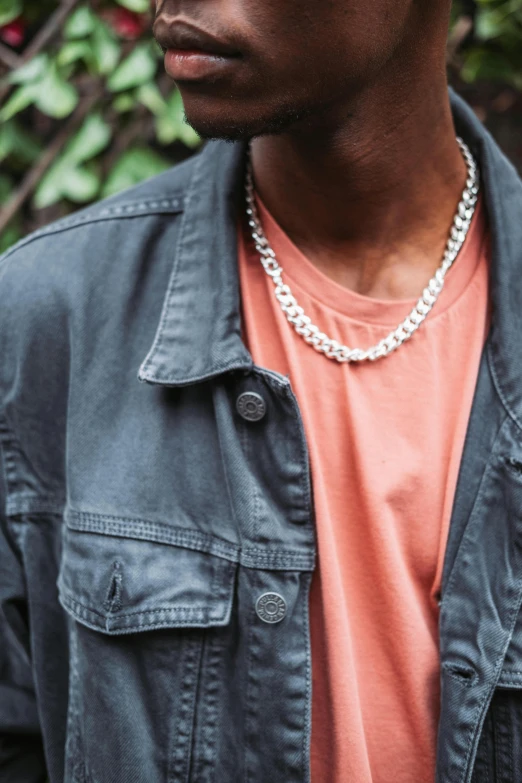 a close up of a person wearing a hat, neck chains, wearing a jeans jackets, silver hues, zoomed out shot