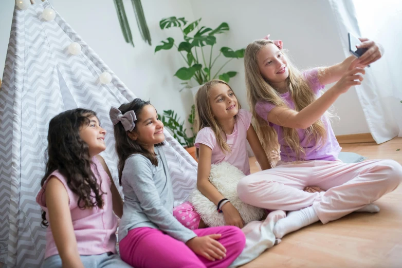 a group of girls sitting on the floor in front of a teepee, a picture, shutterstock, in the bedroom at a sleepover, avatar image, pink clothes, behind the scenes photo