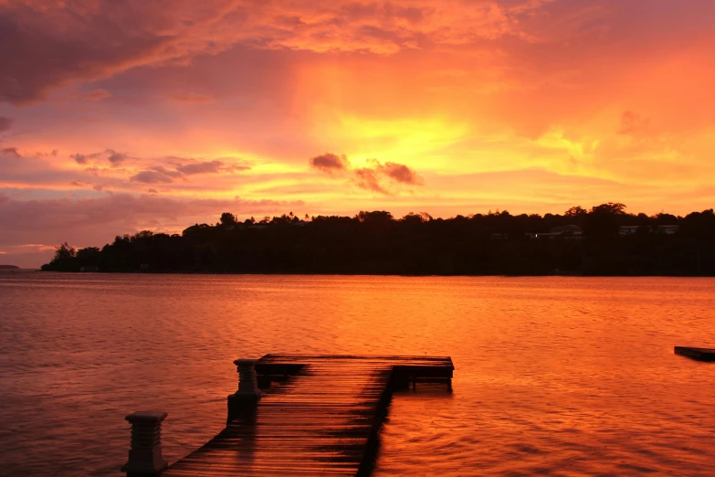 a dock in the middle of a lake at sunset, by Carey Morris, pexels contest winner, hurufiyya, jamaica, sunset red and orange, fire from sky, sunset panorama