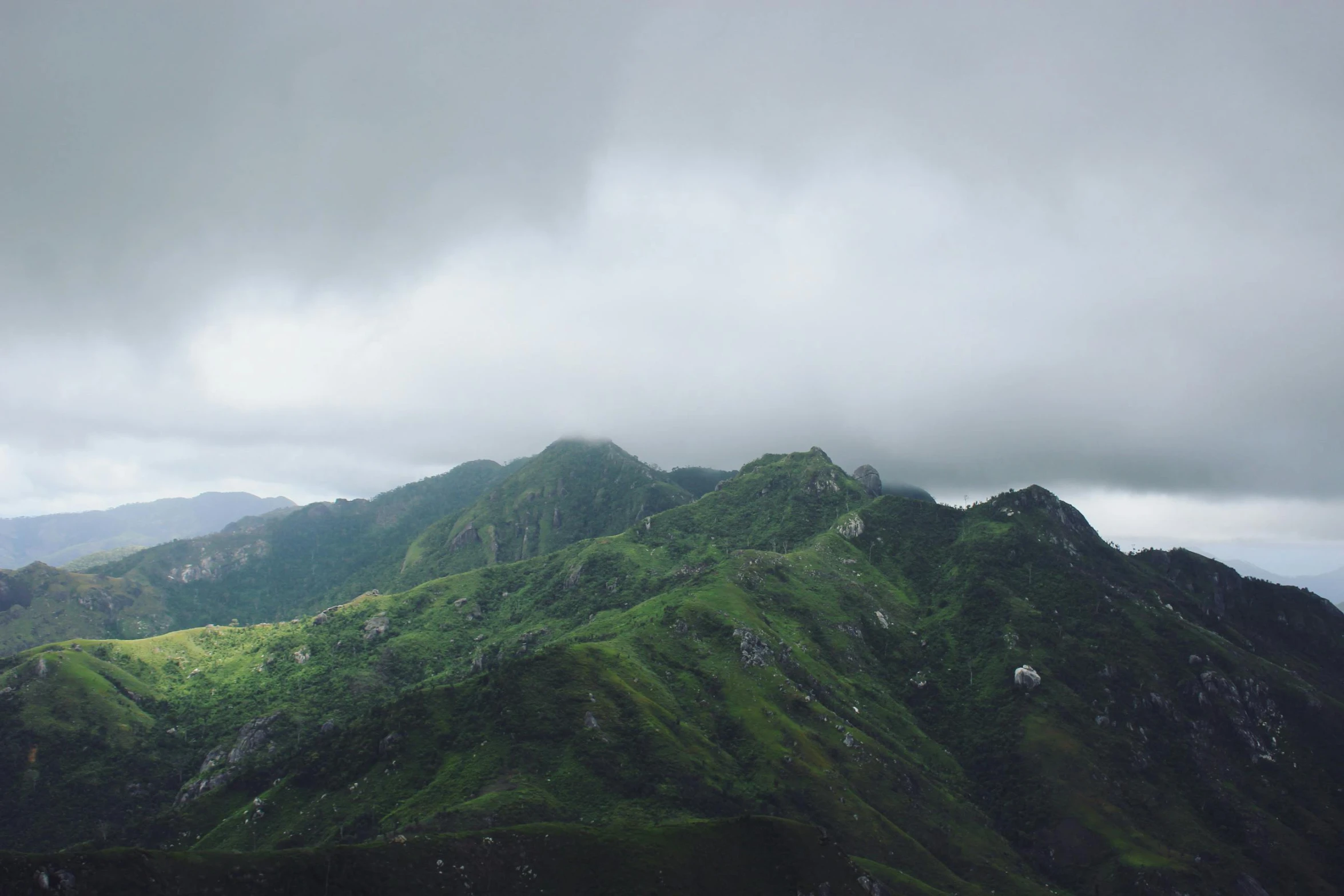 a mountain covered in green grass under a cloudy sky, unsplash, hurufiyya, stormy snowy fiji mountain, under a gray foggy sky, multiple stories, music video