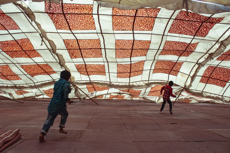 a couple of people that are standing in a room, by Christo, interactive art, kids playing, india, with roulettes in the roof, 15081959 21121991 01012000 4k