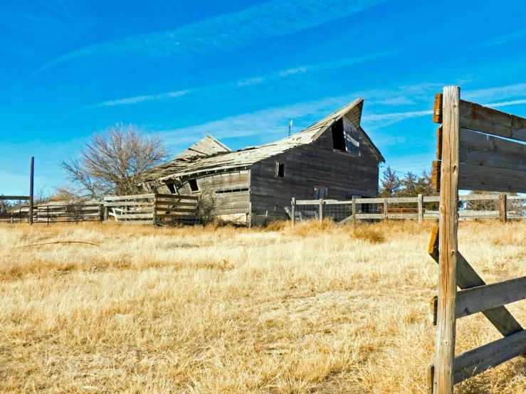 a wooden fence in a field with a barn in the background, by Pamela Ascherson, unsplash, land art, abandoned in a desert, background image, blue sky, slide show