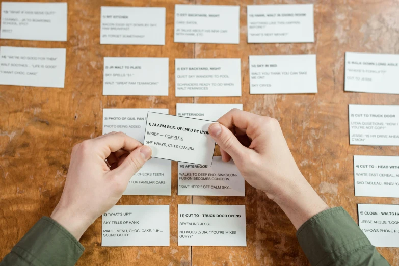 a person holding a business card on top of a table, process art, playing games, random english words, birdseye view, thumbnail