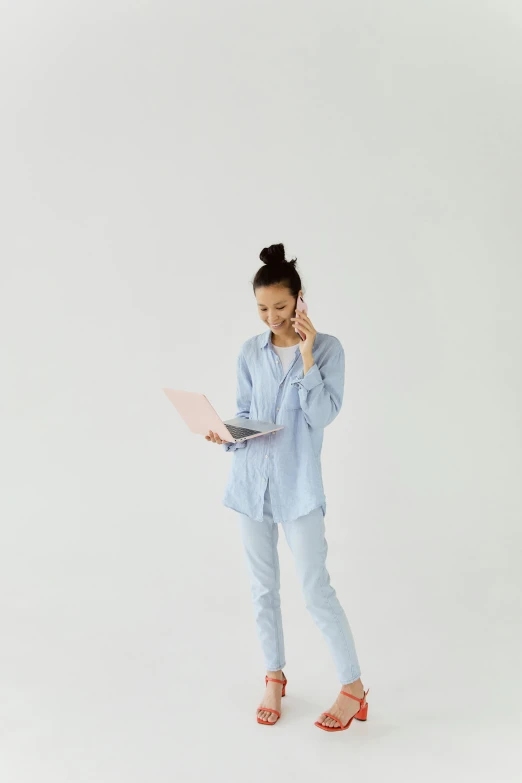 a woman talking on a cell phone and holding a laptop, by Carey Morris, trending on pexels, minimalism, wearing pajamas, pale blue outfit, full body hero, ai researcher