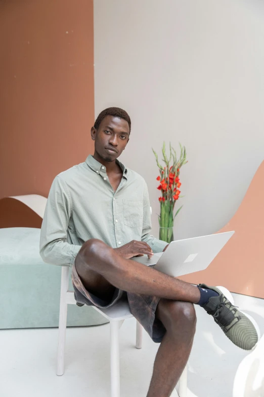 a man sitting on a chair using a laptop, an album cover, inspired by Barthélemy Menn, trending on unsplash, light-brown skin, pastel', full body model, mkbhd