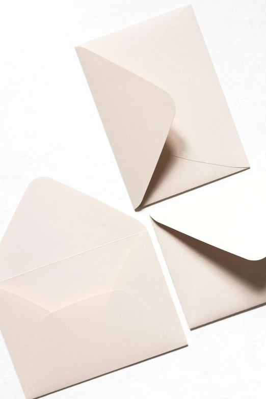 three white envelopes sitting on top of each other, light blush, soft shapes, detailed product image, dark. no text