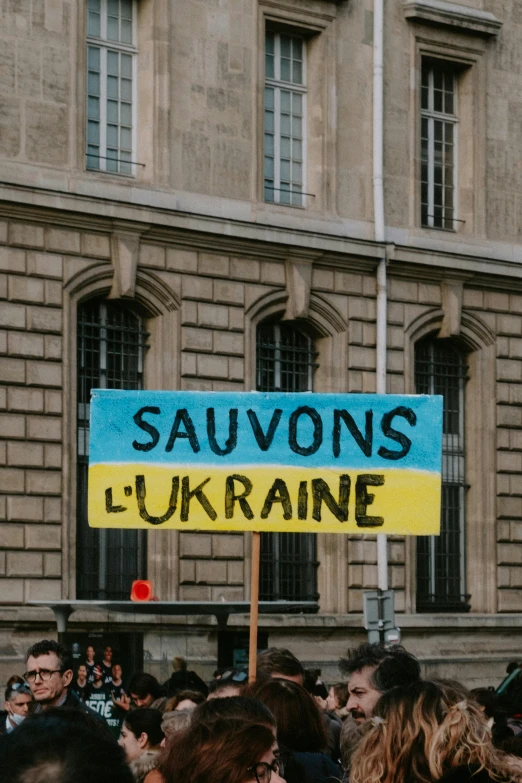 a group of people standing in front of a building, an album cover, trending on unsplash, viennese actionism, ukrainian flag on the left side, traveling in france, cooking oil, placards