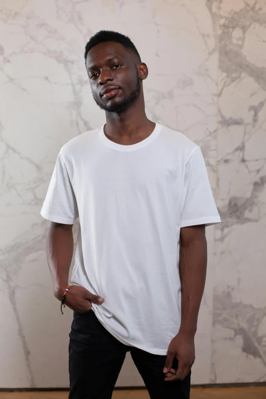 a man standing with his hands in his pockets, by Robbie Trevino, plain white tshirt, large tall, off - white collection, handsome hip hop young black man