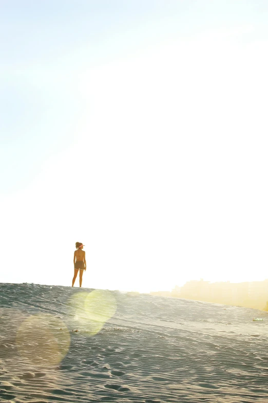 a man riding a wave on top of a surfboard, by Jessie Algie, unsplash, minimalism, standing on a hill, sun glare, panoramic view of girl, standing in sand