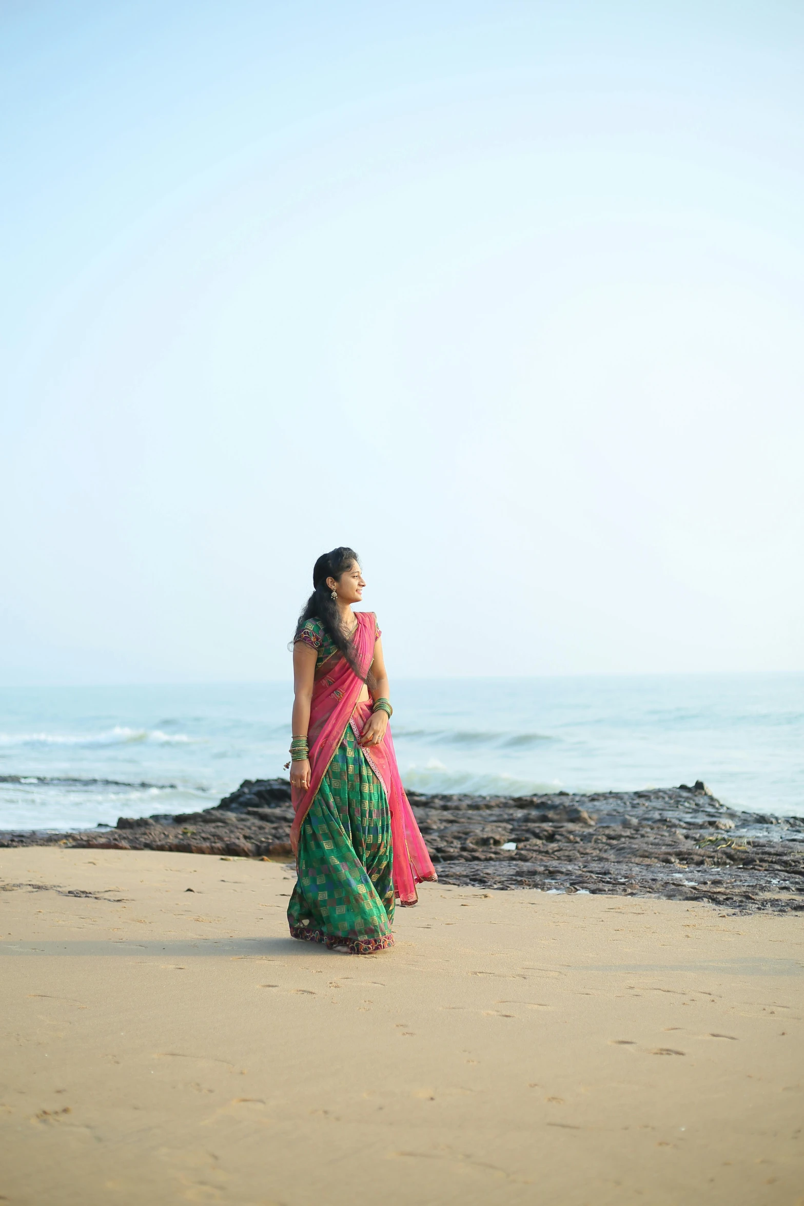 a woman standing on top of a sandy beach, an album cover, inspired by T. K. Padmini, unsplash, movie still 8 k, wearing sari, profile view, early evening