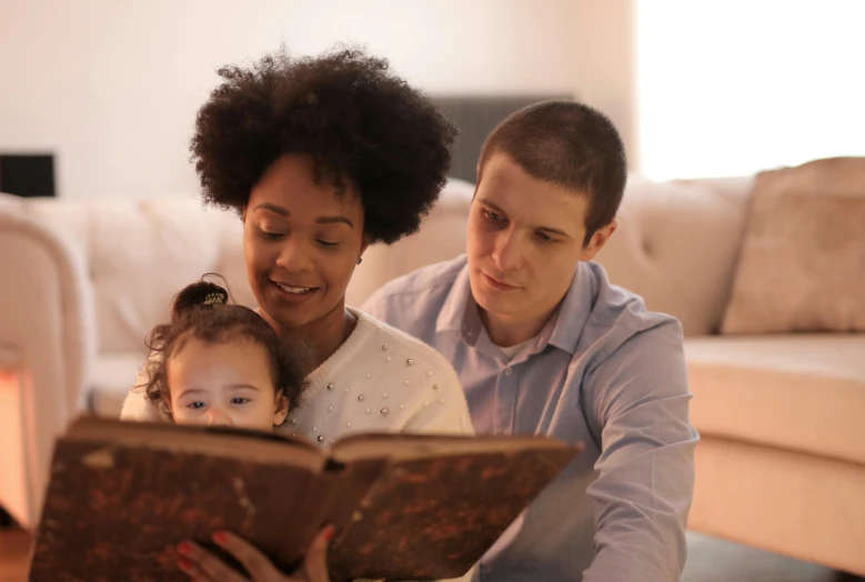 a man and woman reading a book to a child, a photo, pexels, mixed race, fan favorite, brown, rectangle