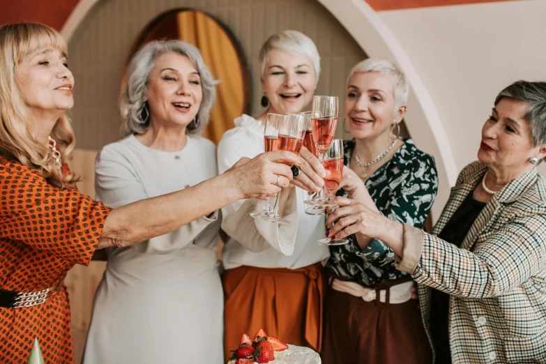 a group of women toasting in front of a cake, by Matija Jama, pexels contest winner, art nouveau, elderly, holding a drink, promo image, middle aged