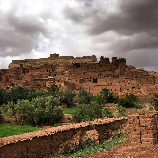 a large brown building sitting on top of a lush green field, pexels contest winner, les nabis, moroccan city, lost city, brooding, from of thrones