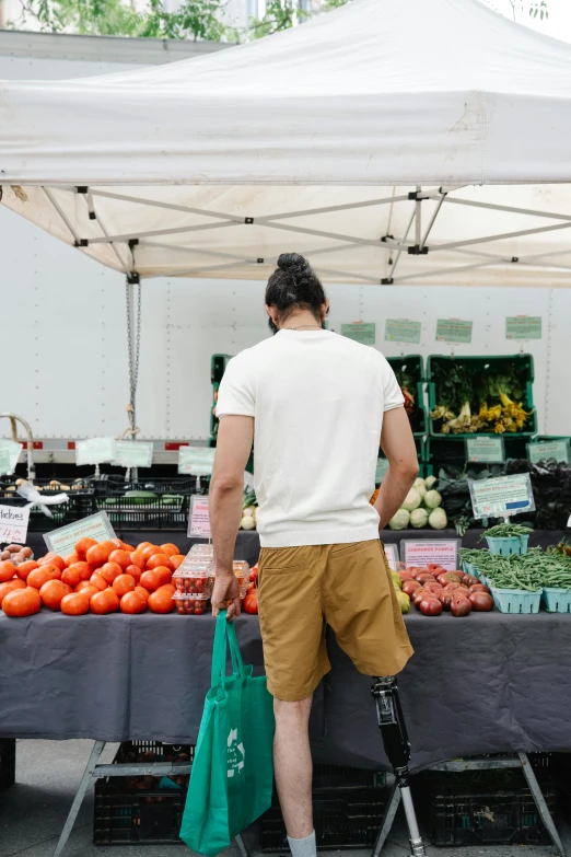 a man standing in front of a produce stand, trending on unsplash, renaissance, wearing pants and a t-shirt, looking from behind, lgbtq, farmer's market setting