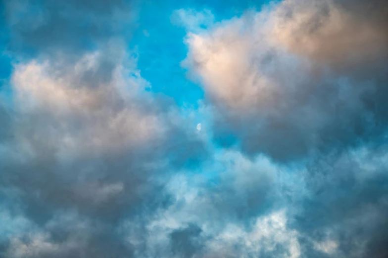 a plane flying through a cloudy blue sky, an album cover, by Daniel Seghers, unsplash, baroque, the cloudy moonlit sky, multicoloured, stormy overcast, low angle 8k hd nature photo